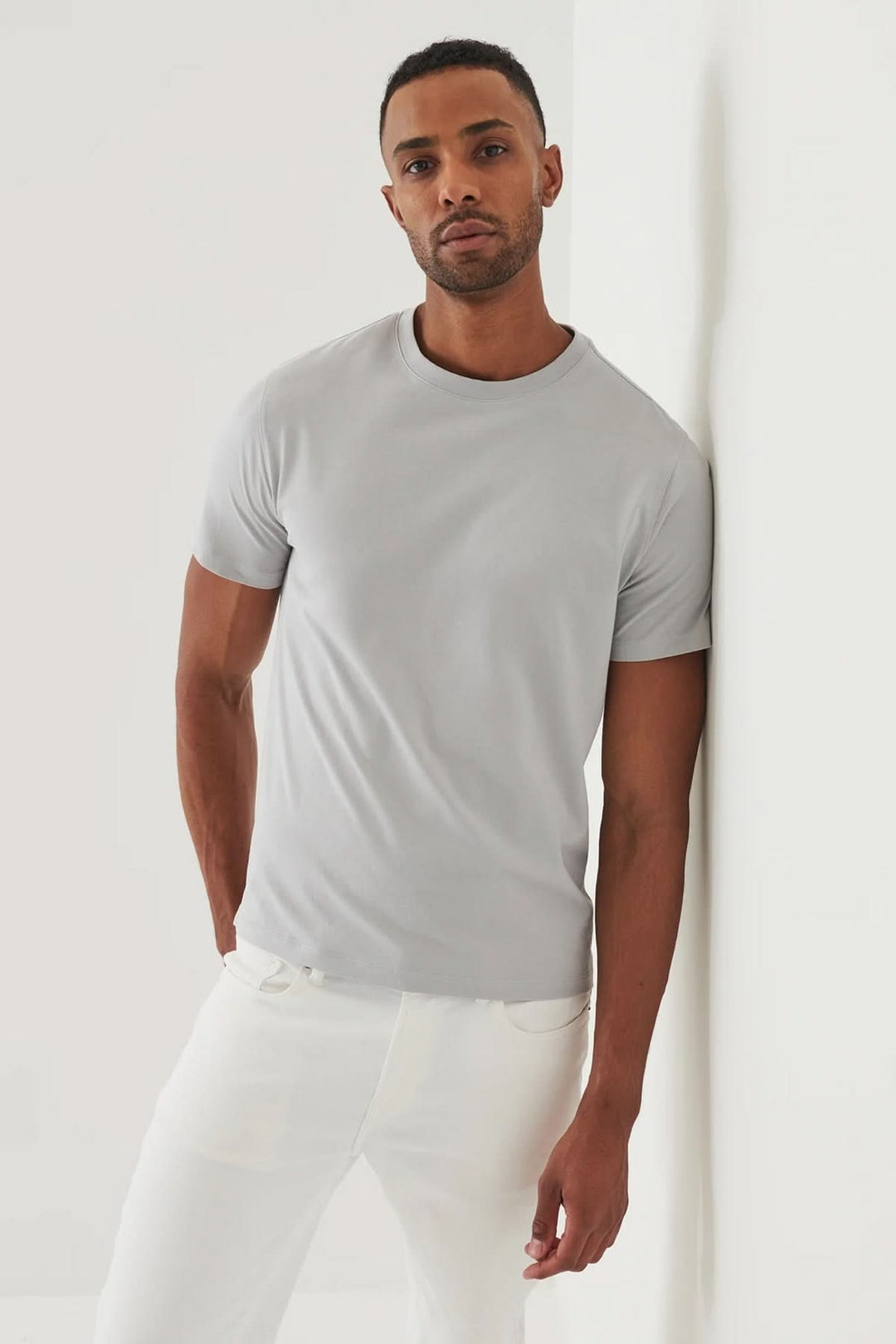 Homme portant un t-shirt minimaliste gris à col rond, style épuré, coupe droite, sur fond neutre.