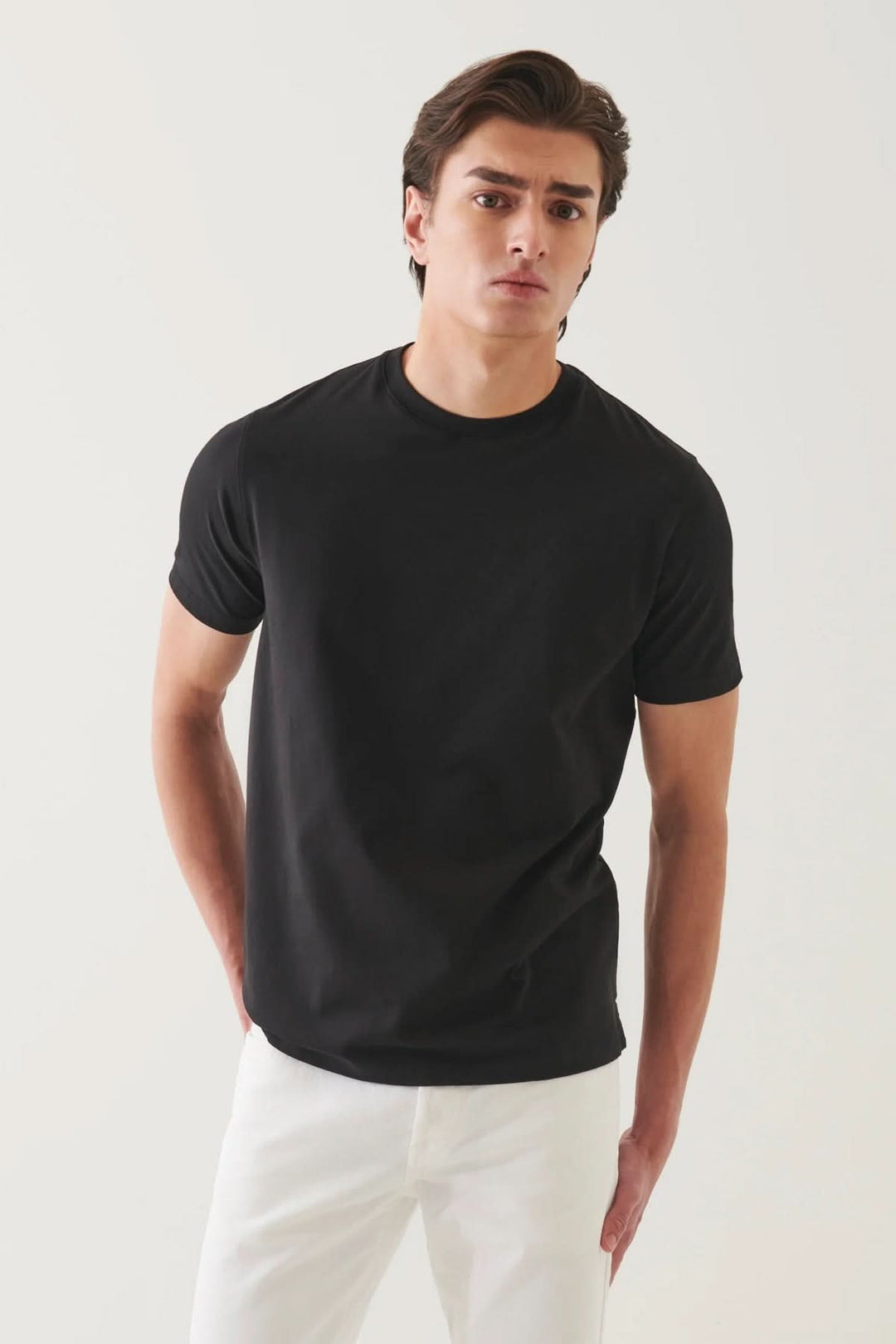 T-shirt minimaliste noir à col rond, coupe droite, style épuré sur modèle masculin, parfait pour looks décontractés.