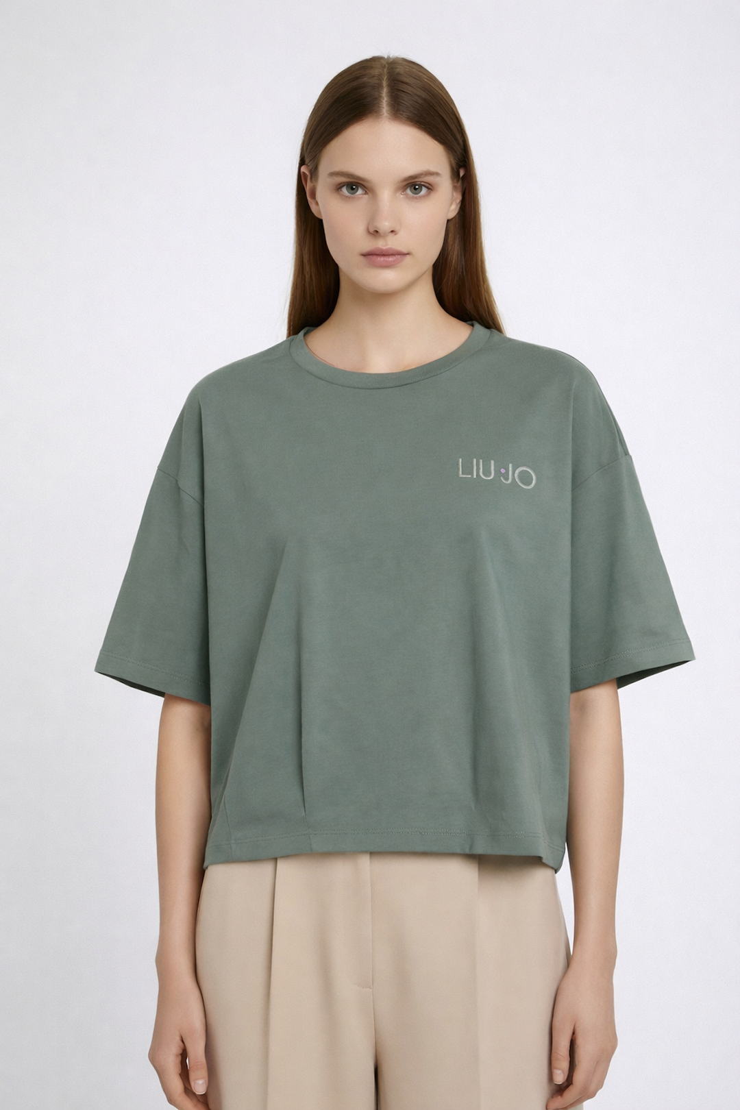 Femme portant un T-shirt oversize avec logo brodé, manches courtes et encolure ronde, style décontracté.
