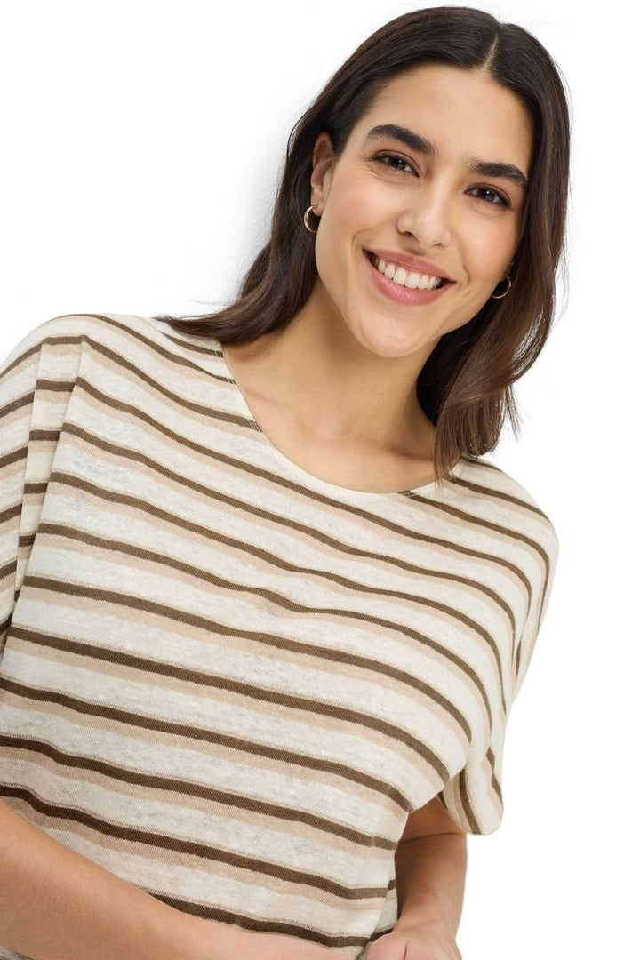 Femme souriante portant un T-shirt rayé CAELENS à manches courtes avec motif à rayures irrégulières et col rond, look décontracté.