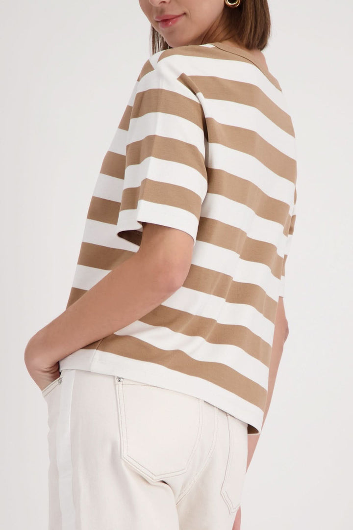 Side view of a model wearing a T-shirt rayé à logo embossé, featuring beige and white stripes and short sleeves, paired with white pants.