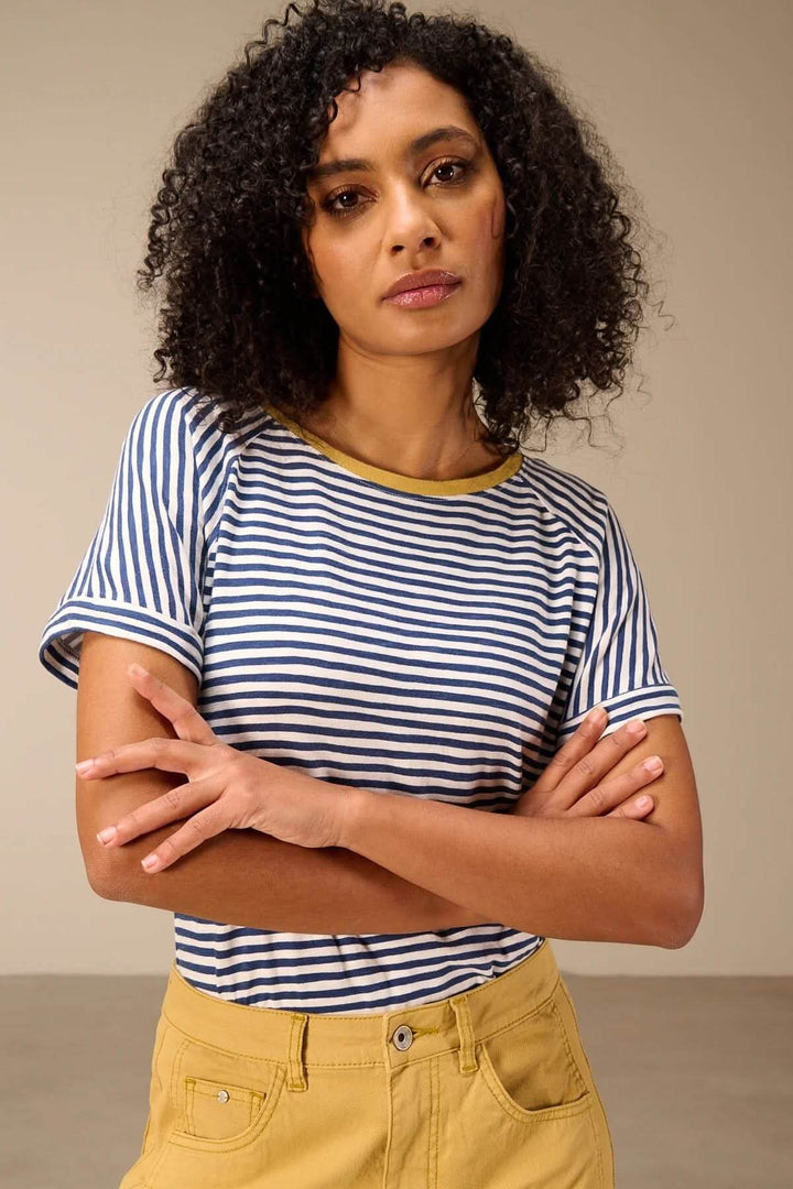 T-shirt rayé manches courtes style raglan porté par une femme, encolure ronde contrastante, manches raglan avec revers, look casual chic.
