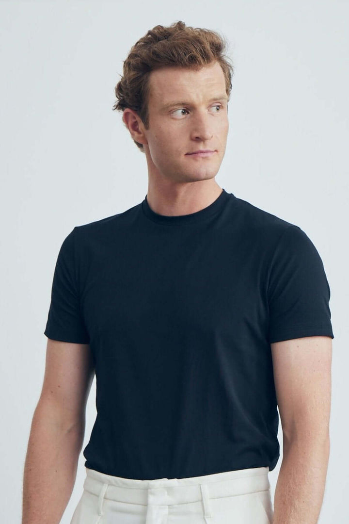 Homme portant un T-shirt uni noir à col rond, offrant confort et style moderne.