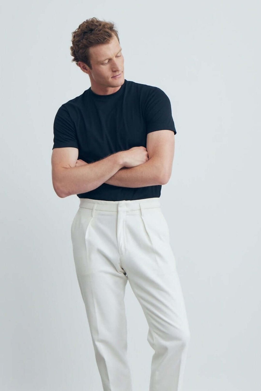 Homme portant un T-shirt uni noir et un pantalon blanc, affichant un style moderne et décontracté.