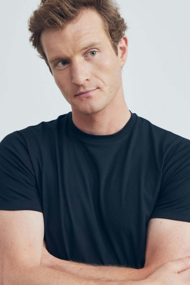 Homme portant un T-shirt uni noir à col rond, fabriqué en tissu extensible 4Flex pour confort optimal.