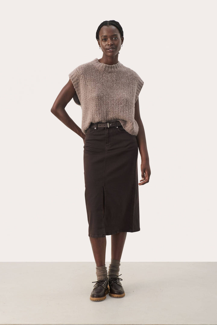 Modèle portant un tricot beige sans manches avec une jupe noire, idéal pour les superpositions et un style contemporain.