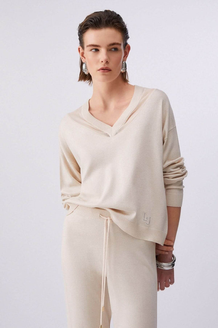 Femme portant un tricot col en V à manches longues avec un look décontracté et élégant, idéal pour le quotidien, tissu doux et léger.