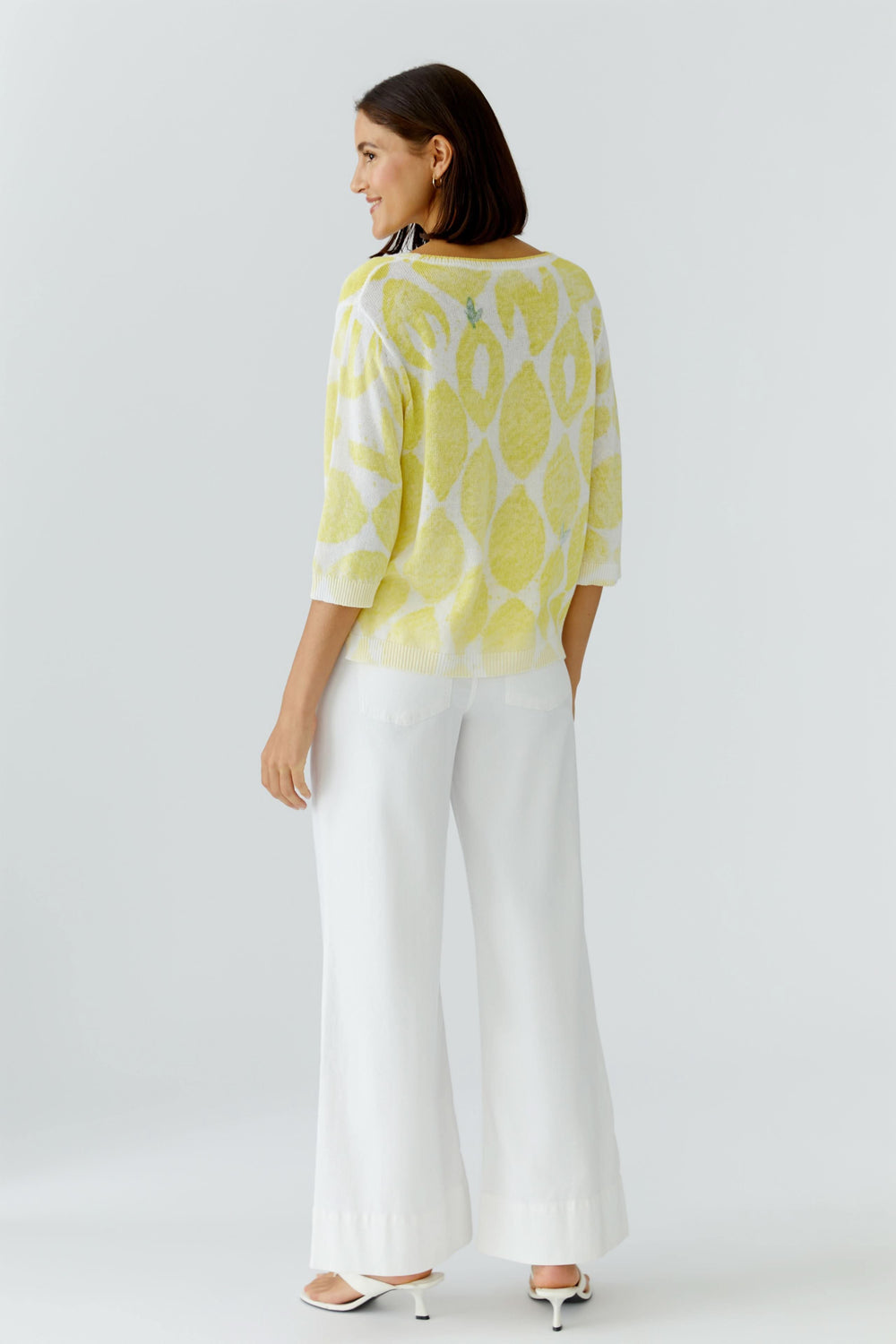 Femme portant un tricot léger imprimé à manches 3/4, coupe fluide, motif distinctif jaune, idéal pour un look décontracté et confortable.