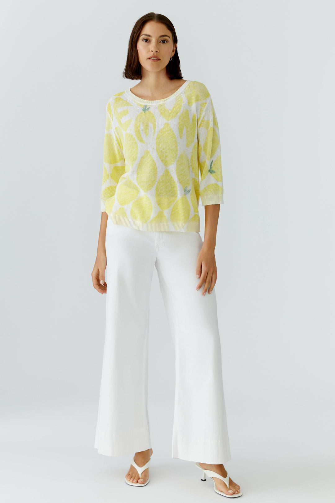 Femme portant un tricot léger imprimé à manches 3/4, coupe fluide jaune, confort optimal, motif distinctif sur fond blanc.