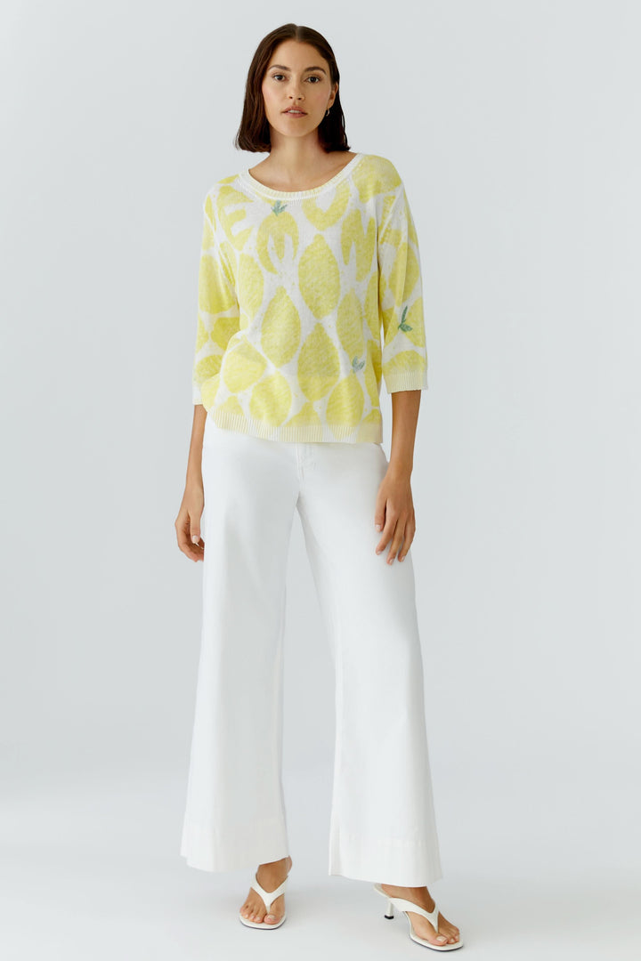 Femme portant un tricot léger imprimé à manches 3/4, coupe fluide jaune, confort optimal, motif distinctif sur fond blanc.