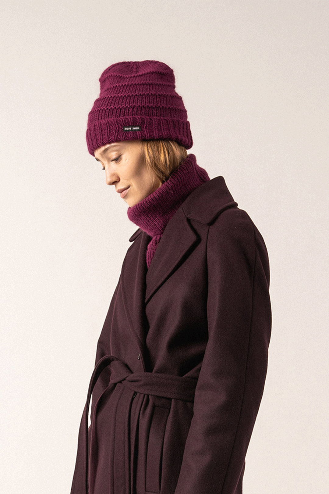 Femme portant une tuque prune élégante avec un manteau, parfaite pour l'hiver.