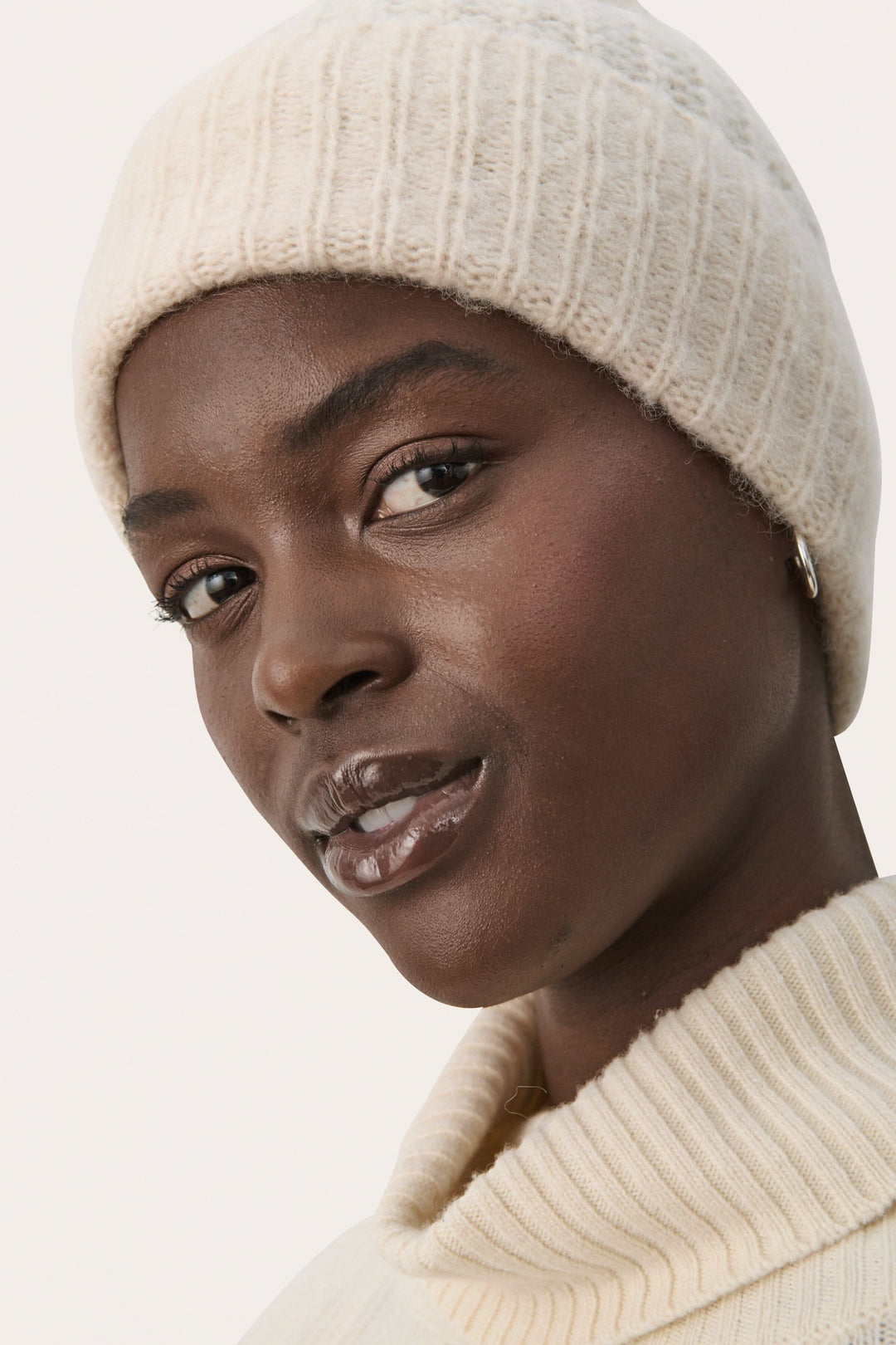 Femme portant une tuque moelleuse beige, design simple, parfaite pour les journées froides.