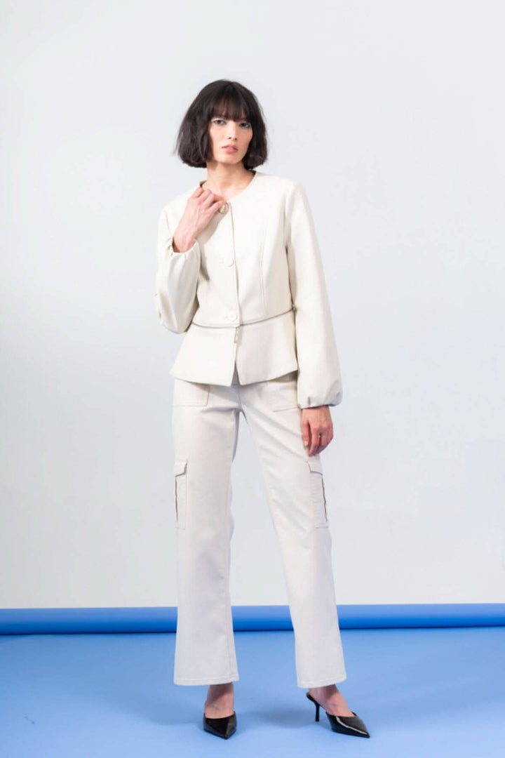 Femme portant une veste péplum boutonnée en PU et un pantalon cargo, look chic et moderne.
