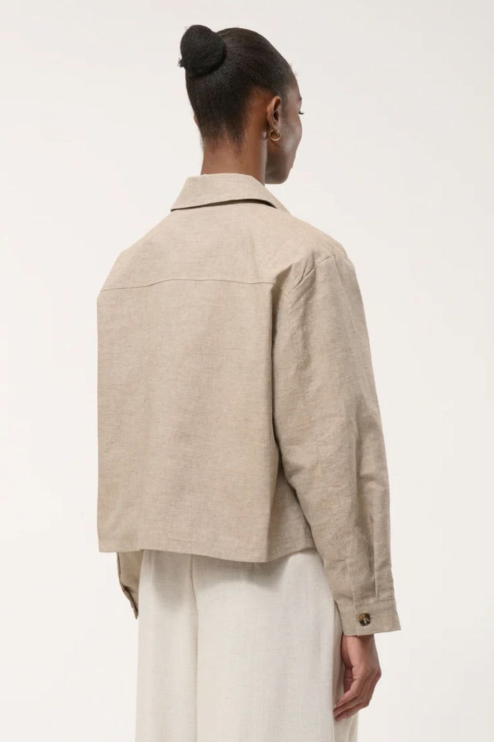 Veste chemise courte beige vue de dos, élégante et utilitaire, avec coupe structurée et poches plaquées.