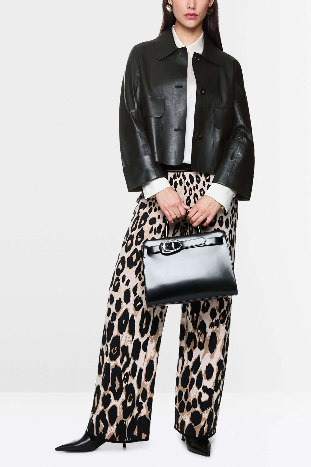 Veste coupe moderne en cuir avec col classique, portée sur chemise blanche et pantalon imprimé, look chic et affirmé.