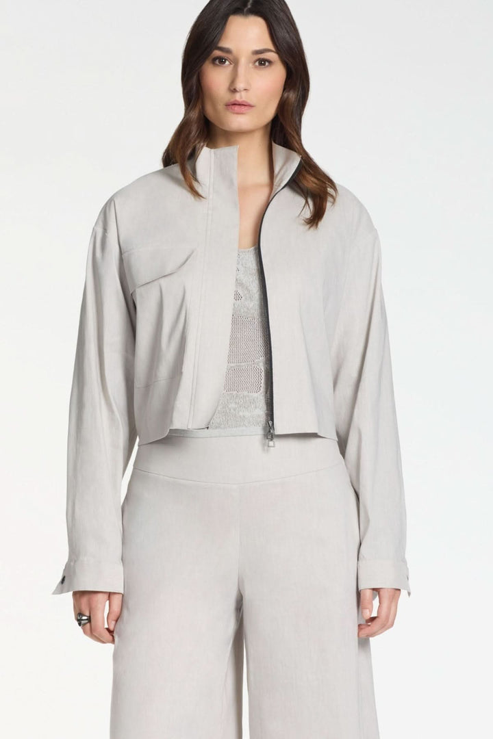 Femme portant une veste courte à zip col montant gris avec manches longues, idéale pour un look moderne et structuré.