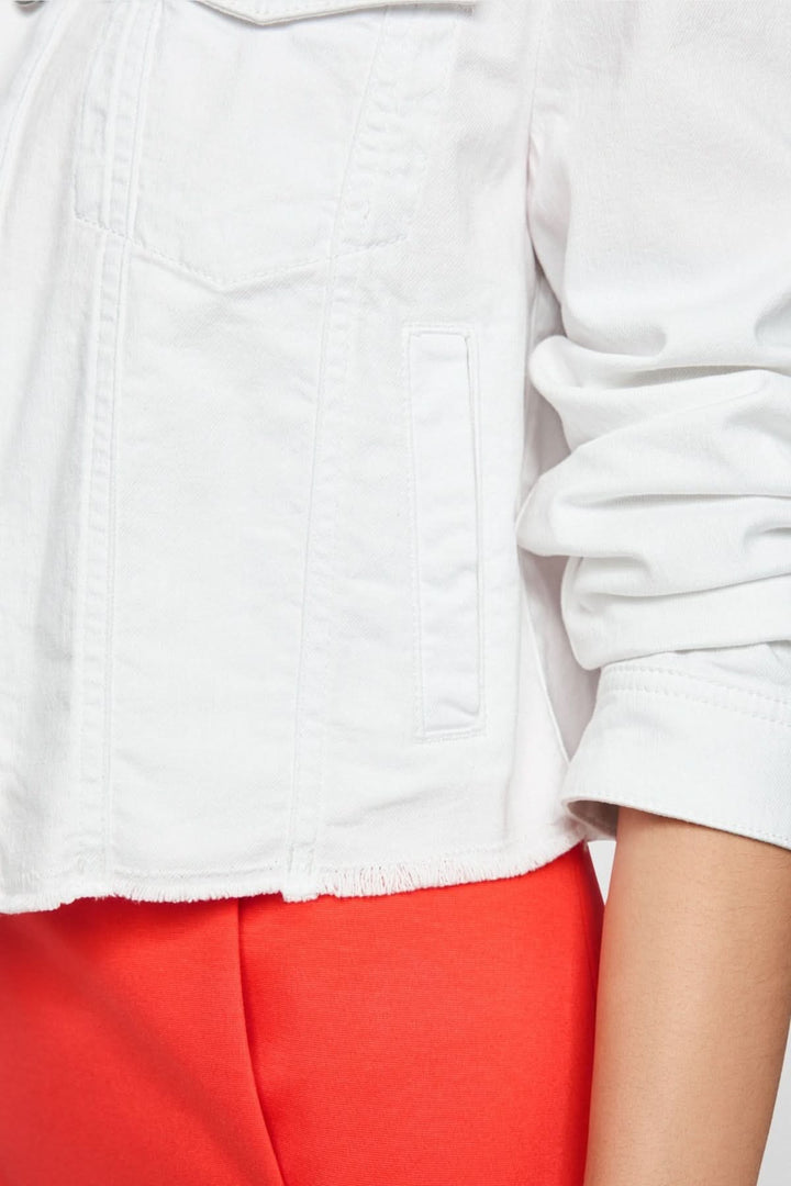 Gros plan sur une veste en denim écourtée blanche avec détails de poches et manches longues, portée avec un pantalon rouge.