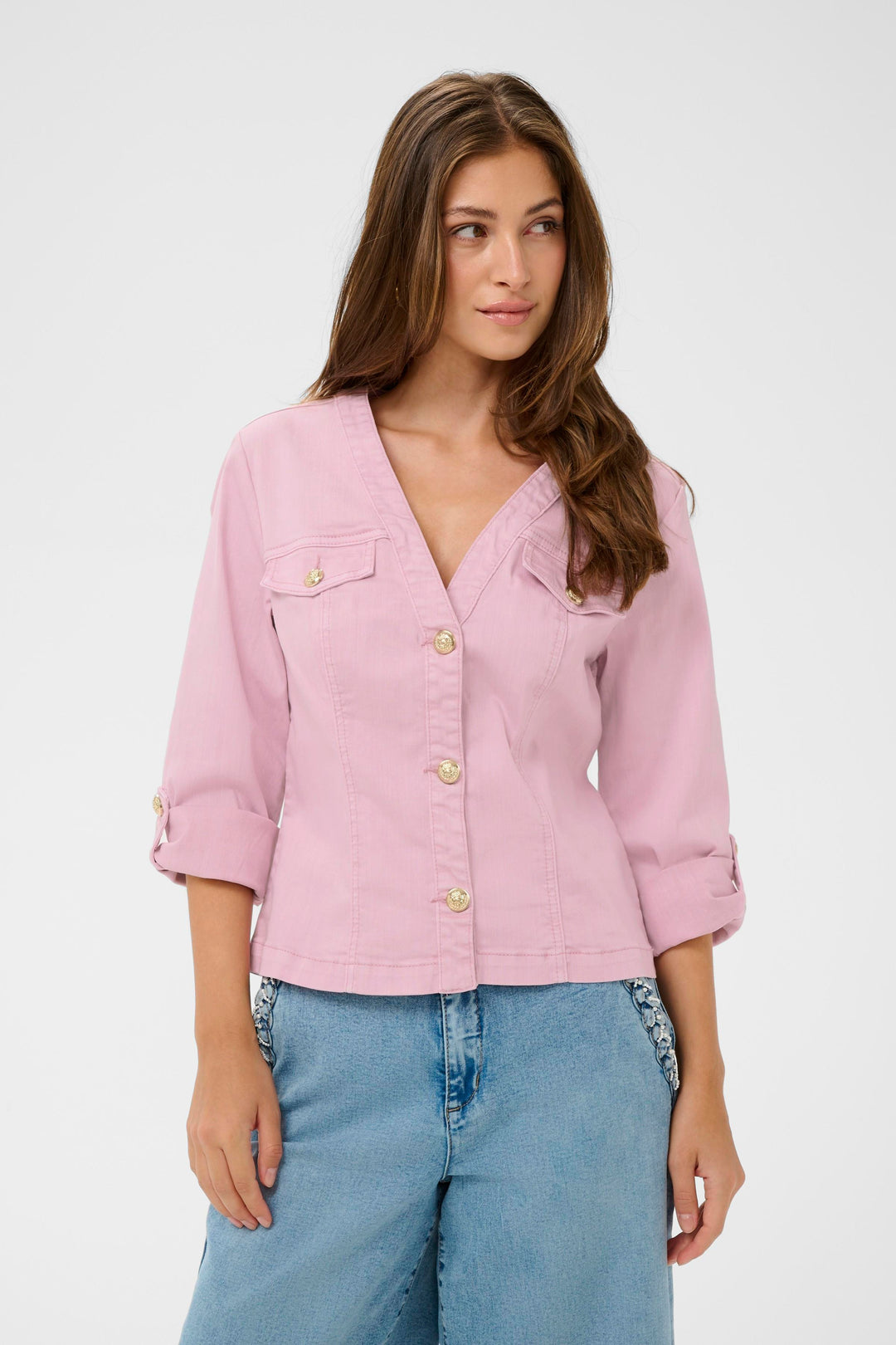 Femme portant une Veste en jean Visti rose avec boutons décoratifs, coupe ajustée et encolure en V, associée à un jean décontracté.