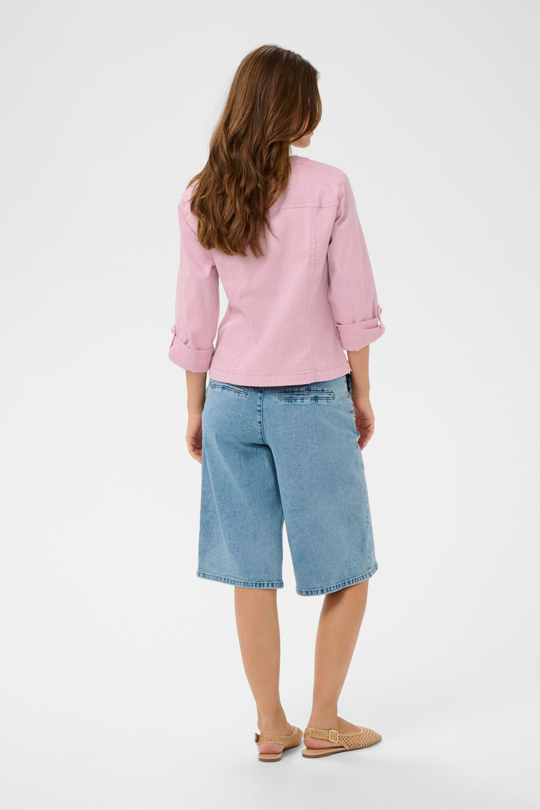 Femme portant une veste en jean rose avec une coupe ajustée et féminine, vue de dos, illustrant la collection Veste en jean Visti.