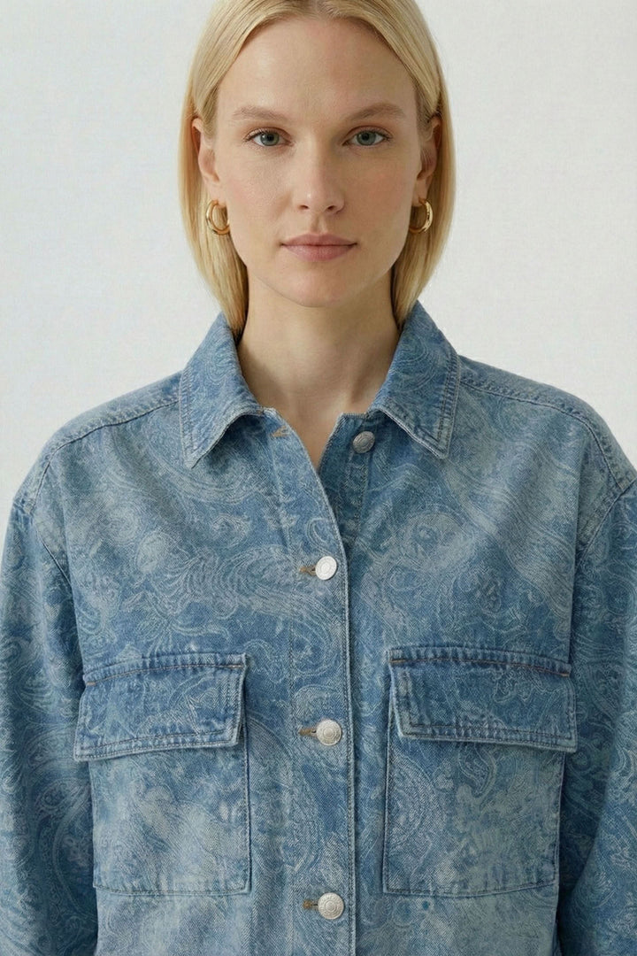Femme portant une veste en jean imprimée avec motif cachemire et coupe structurée, col chemise classique et fermeture boutonnée.