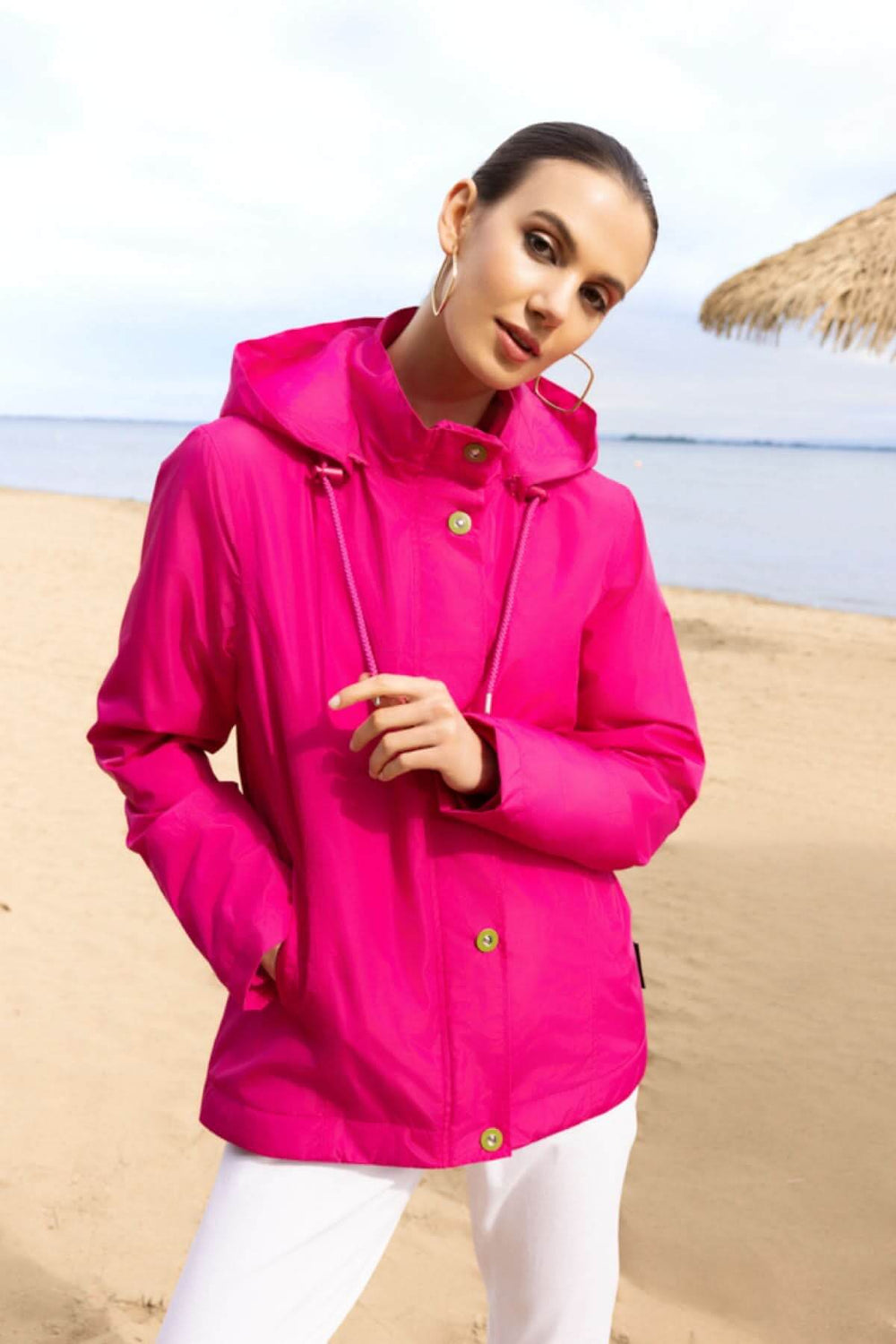 Veste légère à capuche rose pour un look moderne sur une plage.