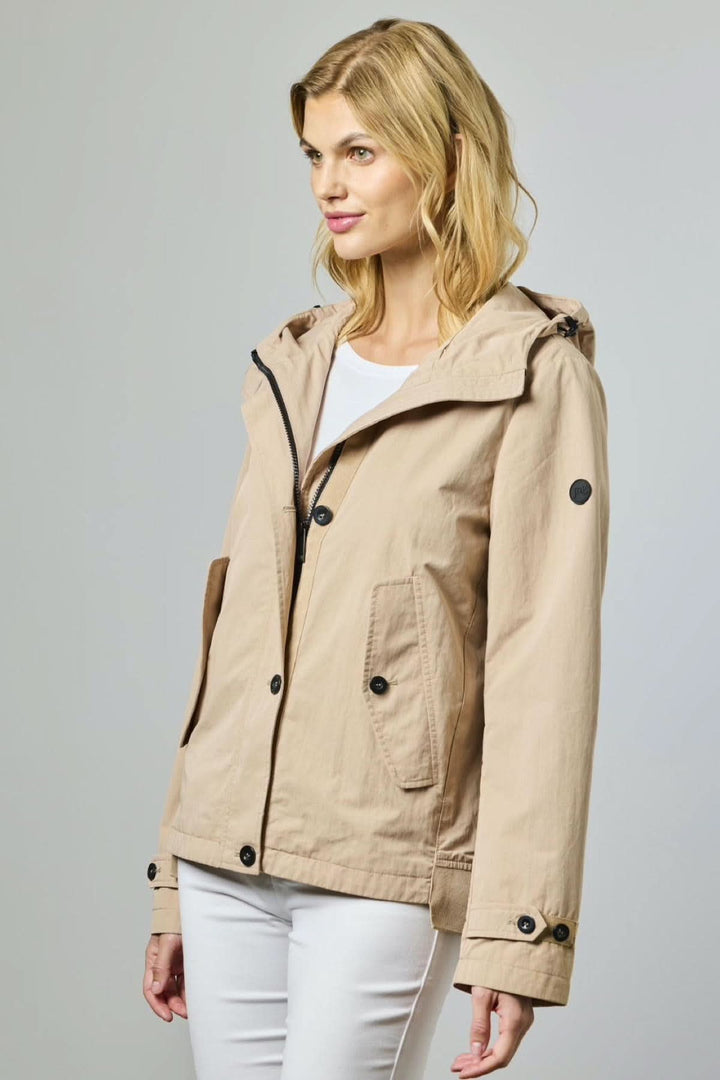 Femme portant une veste légère à capuche utilitaire beige, coupe droite, idéale pour la mi-saison, offrant confort et élégance.