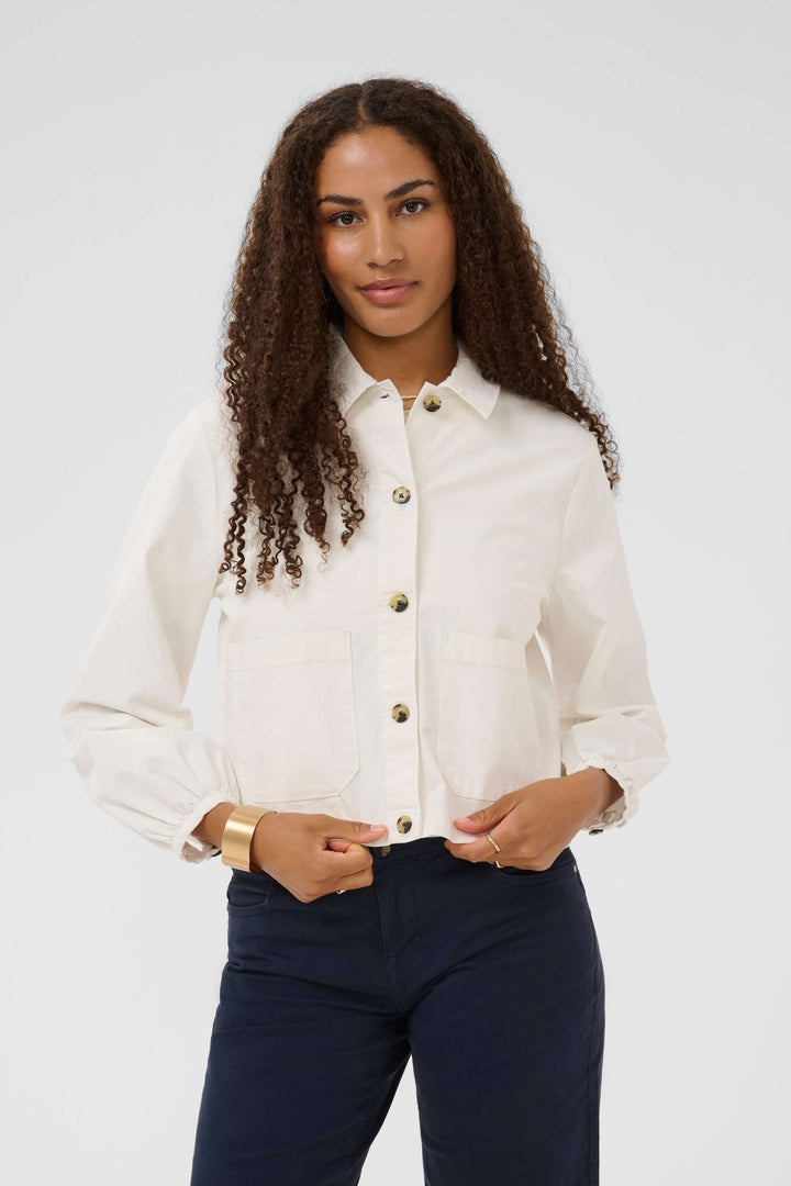 Modèle portant une veste légère rayée à boutons avec col chemise et poches plaquées, idéale pour un look moderne et intemporel.
