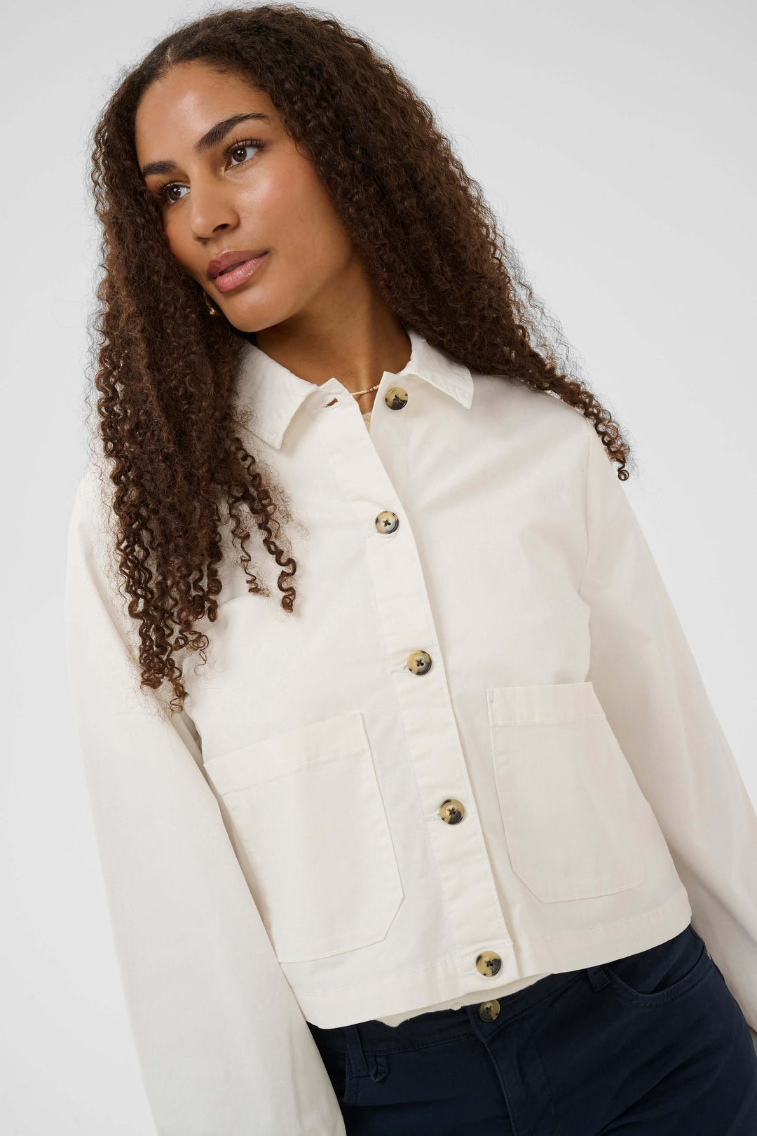 Veste légère rayée à boutons avec col chemise, manches longues et poches, portée par un mannequin, idéal pour une tenue moderne et structurée.
