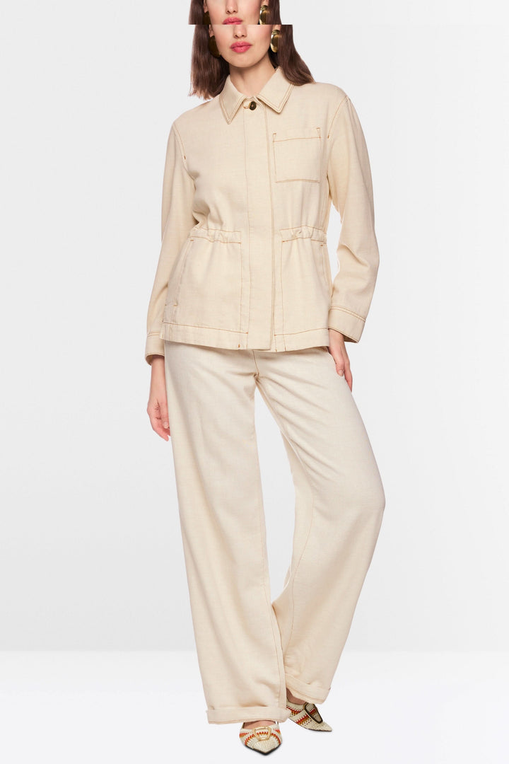 Modèle portant une veste légère à taille ajustable, avec col chemise structuré et fermeture boutonnée, style contemporain et épuré.