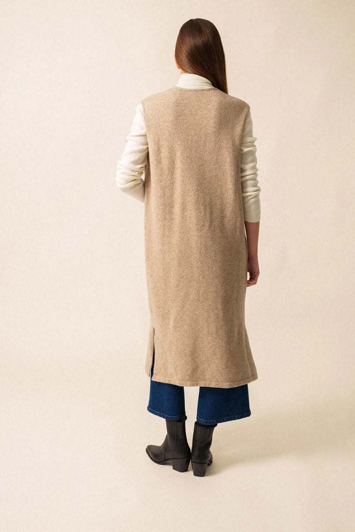 Veste longue sans manches en maille, coupe droite, vue arrière, portée sur un pull et un jean.