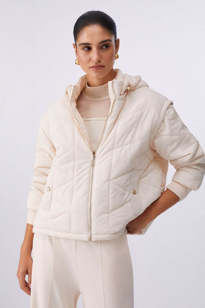 Femme portant une veste matelassée à capuchon élégante, avec rembourrage léger et fermeture à glissière, idéale pour la mi-saison.