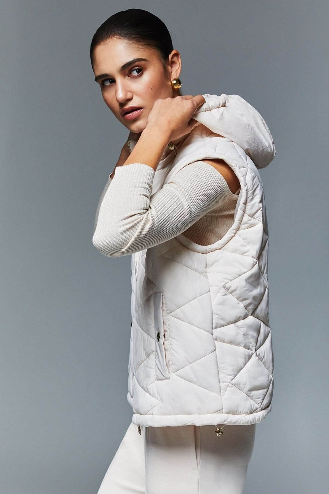 Femme portant une veste matelassée à capuchon blanche avec design moderne et élégant, idéale pour la mi-saison, avec rembourrage léger.