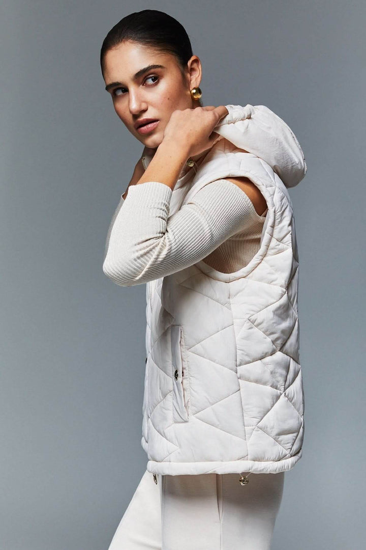 Femme portant une veste matelassée à capuchon blanche avec design moderne et élégant, idéale pour la mi-saison, avec rembourrage léger.