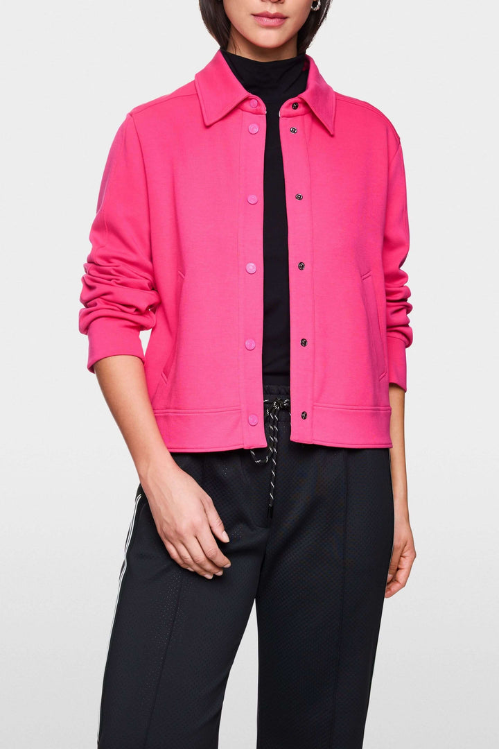Veste moderne rose avec col chemise, portée sur un t-shirt noir avec un look décontracté.