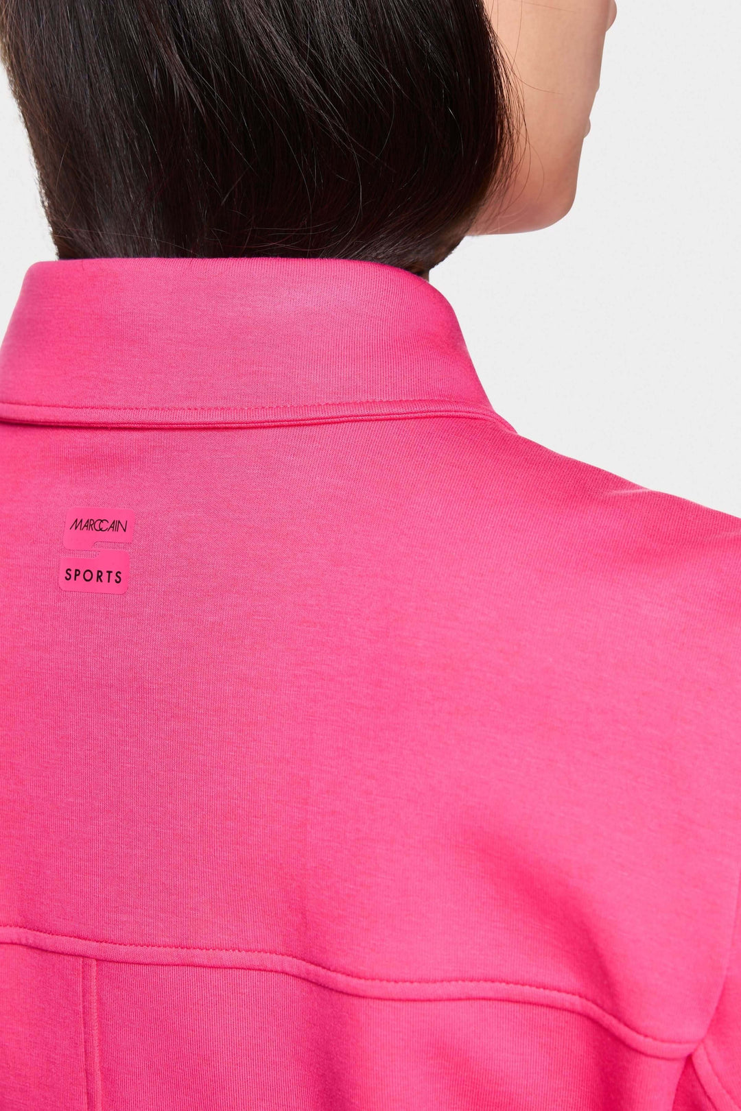 Détail du col d'une veste moderne rose, mettant en avant la marque et le style décontracté.