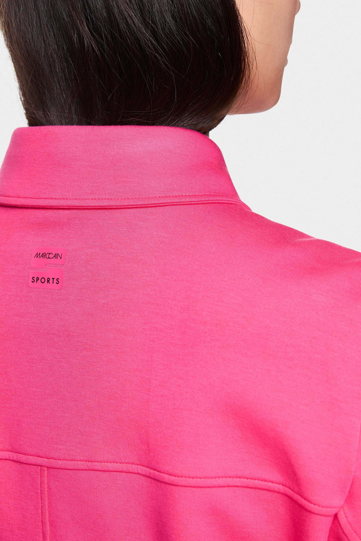 Détail du col d'une veste moderne rose, mettant en avant la marque et le style décontracté.