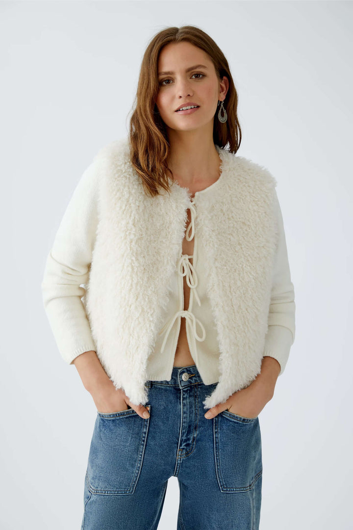 Veste sans manches en fausse fourrure blanche avec coupe moderne et fermeture à crochets.