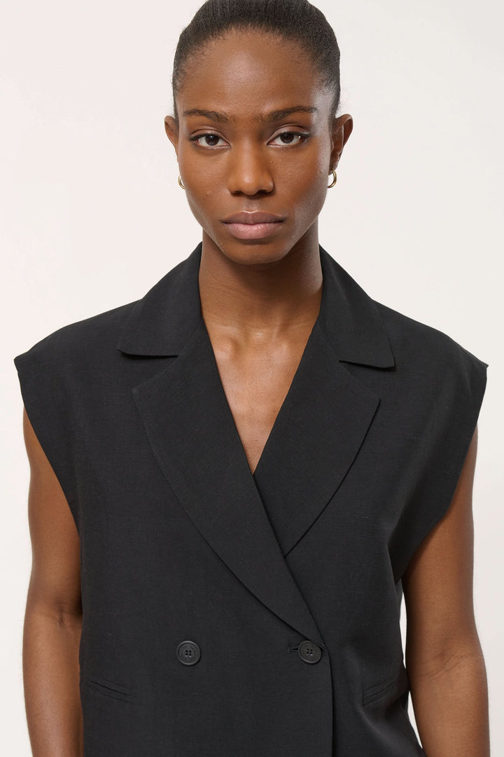 Femme portant une veste tailleur Loric sans manches, coupe droite et col tailleur, ajoutant une touche moderne et structurée à sa tenue.