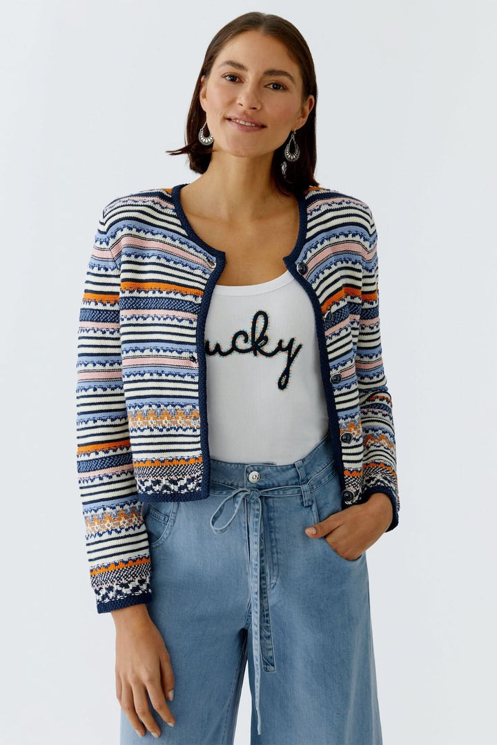 Veste tricot à motifs jacquard boutonnée portée par une femme, ajoutant élégance et style à la tenue, parfaite pour superposition.
