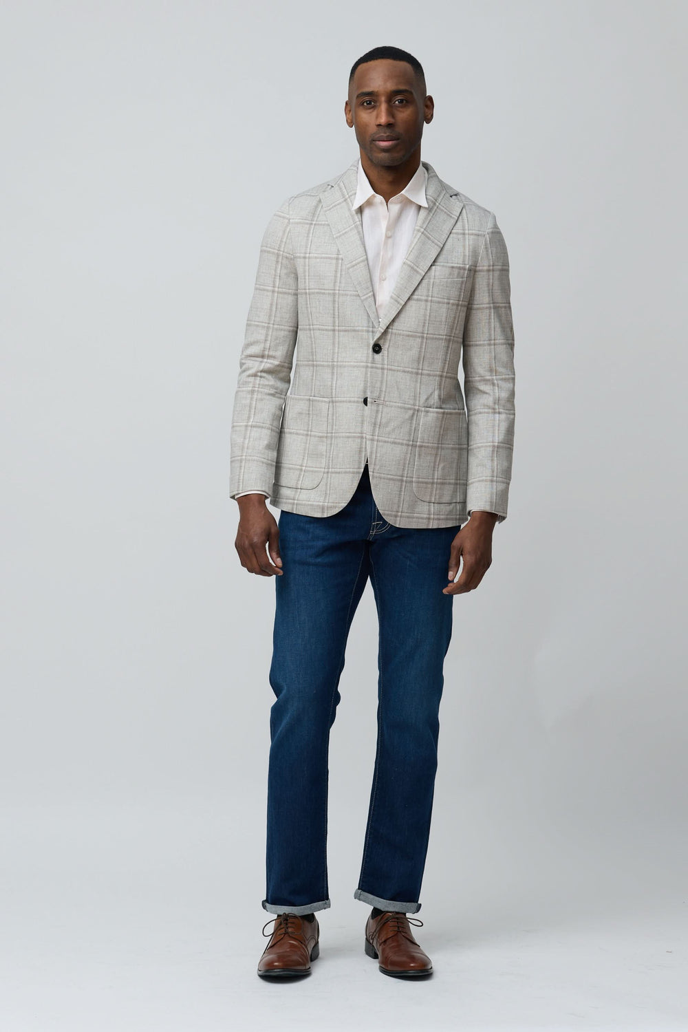 Homme portant un veston à carreaux texturés avec un jean, look moderne et décontracté.