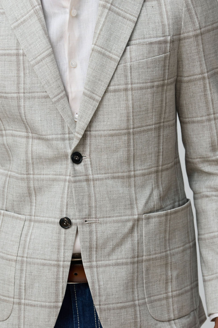 Homme portant un veston à carreaux texturés beige avec chemise blanche, style moderne et décontracté.
