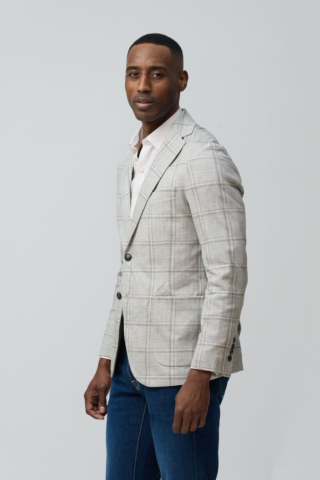 Homme portant un veston à carreaux texturés avec un jean, style moderne et décontracté.