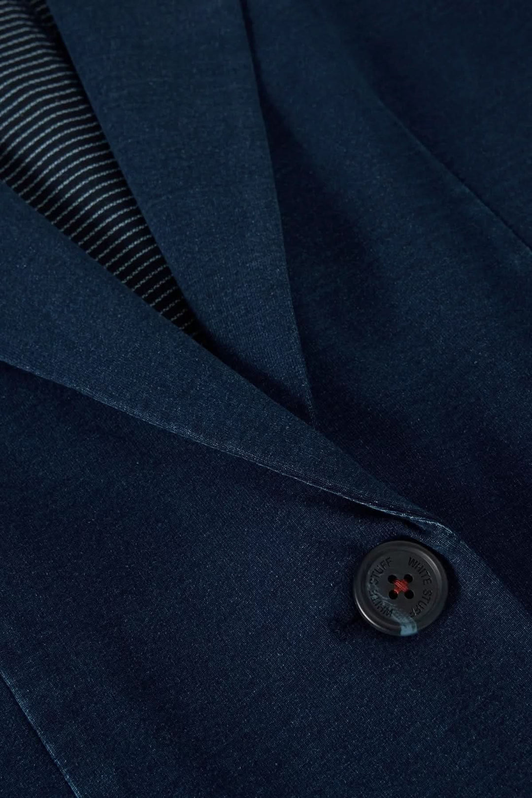 Détail de veston décontracté en denim, couleur bleu marine, avec col tailleur et bouton discret.