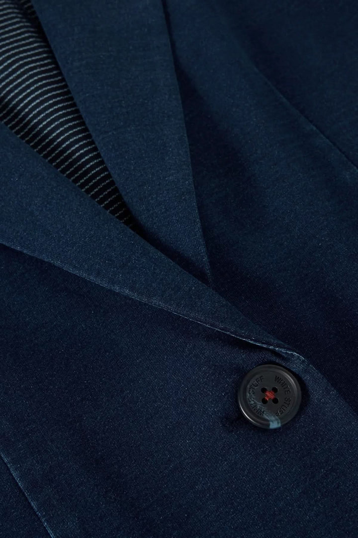 Détail de veston décontracté en denim, couleur bleu marine, avec col tailleur et bouton discret.