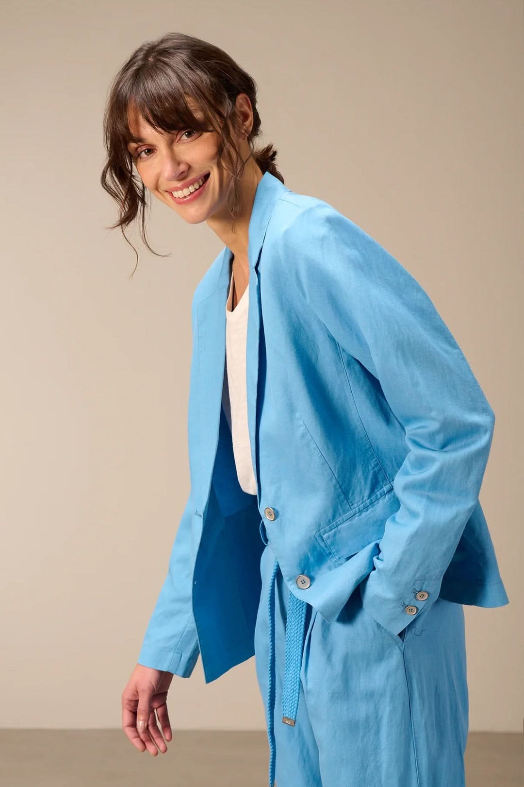 Femme portant un veston léger à coupe droite bleu avec col tailleur classique et manches longues, idéal pour un style moderne.