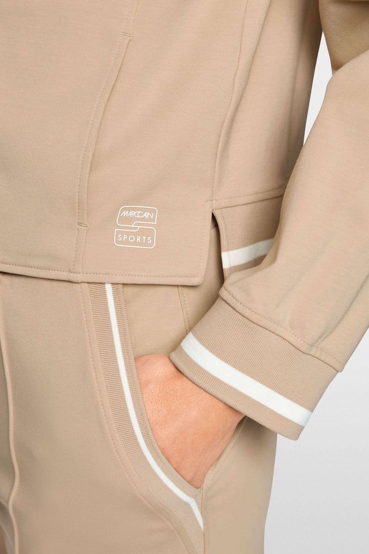 Veston sportif à détails rayés, coupe courte beige avec capuchon à cordon, parfait pour un look chic et décontracté moderne.