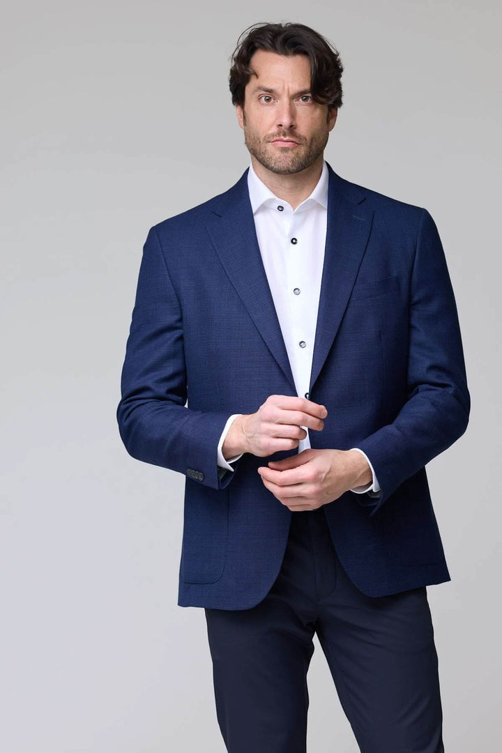 Homme portant un veston structuré à micro motif bleu, idéal pour le bureau et les occasions habillées. Décris moi le produit en français.