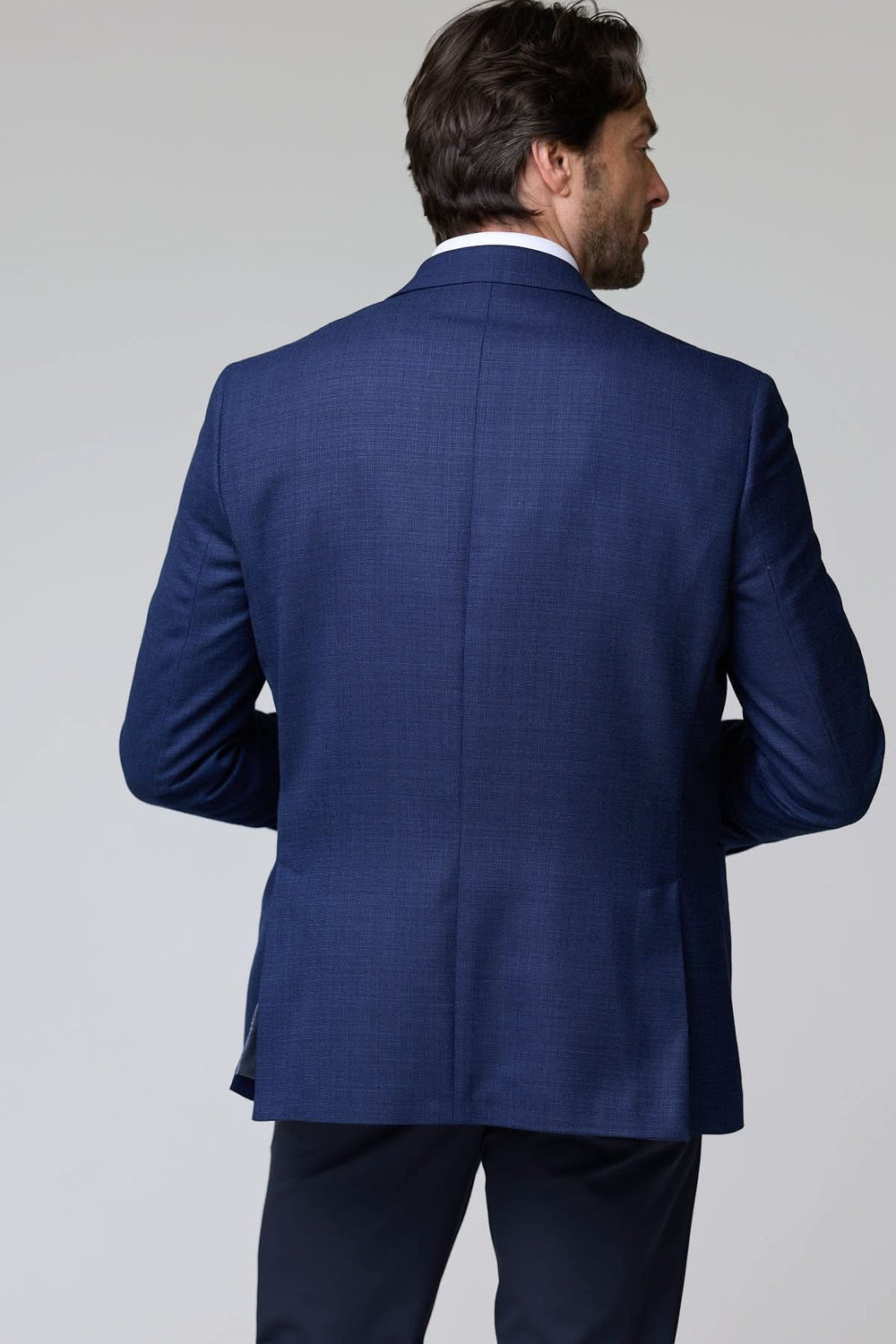 Homme portant un veston structuré à micro motif de dos, mettant en valeur la texture élégante et raffinée du tissu.