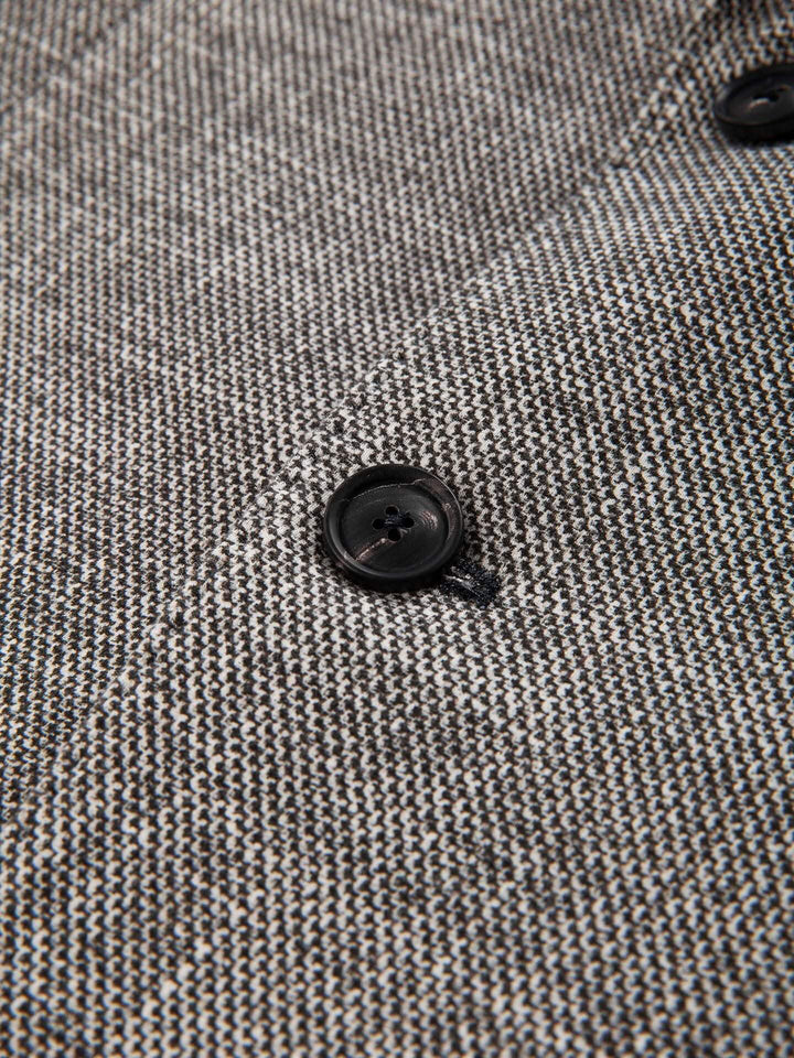 Détail du veston texturé avec bouton en corne et texture raffinée.