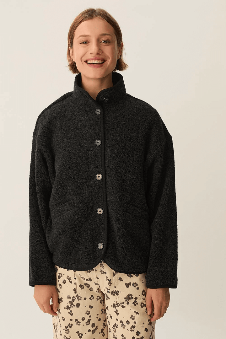 Veste Zlavina boutonnée en laine bouclée portée avec col montant et boutons apparents, idéale pour l'hiver et la mi-saison.